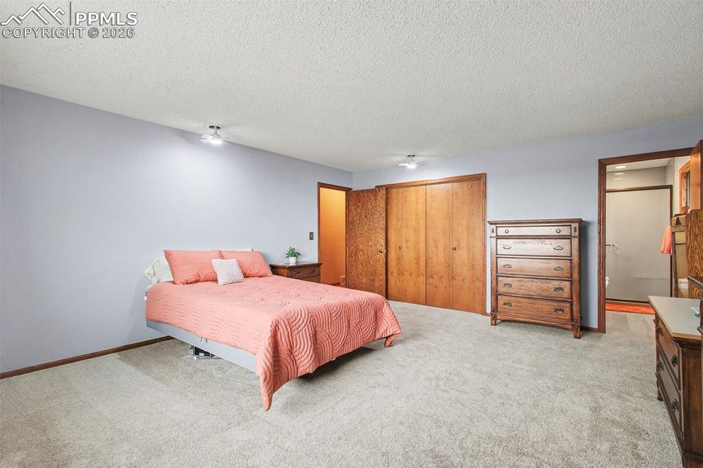 Bedroom featuring a closet, light colored carpet, a textured ceiling, and a ceiling fan