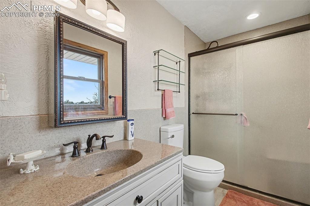Bathroom featuring vanity, a stall shower, and a textured wall