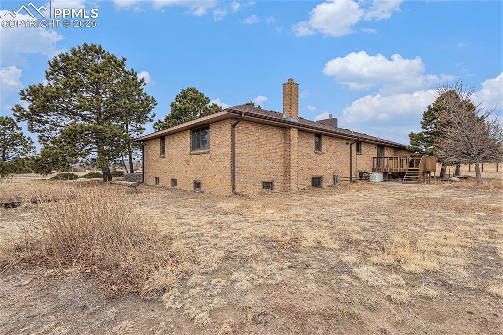 Rear view of house featuring a wooden deck, a chimney, and brick siding
