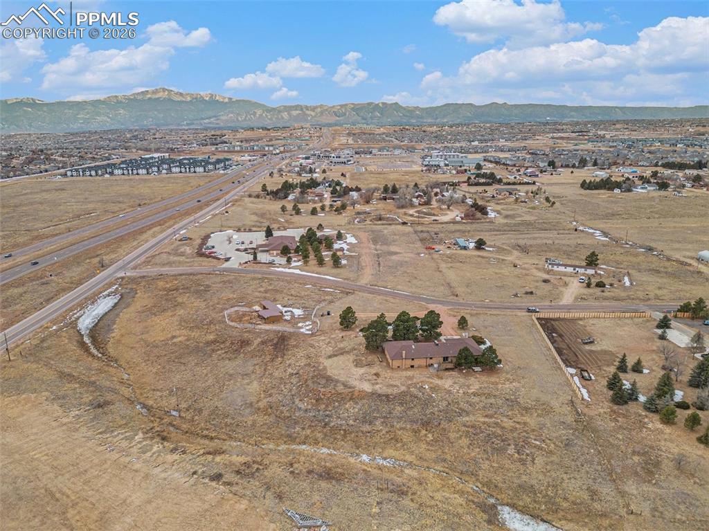 Aerial view of property and surrounding area featuring a mountain backdrop and rural landscape