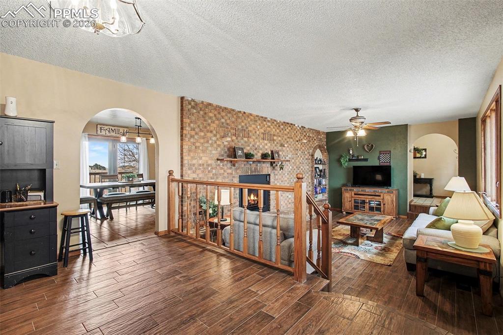 Living room featuring arched walkways, a textured ceiling, wood finish floors, and a ceiling fan
