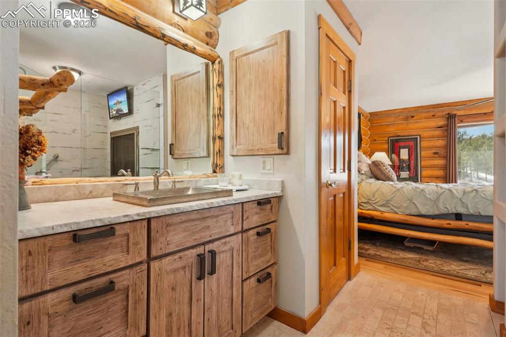 Ensuite bathroom with rustic walls, vanities and tile flooring