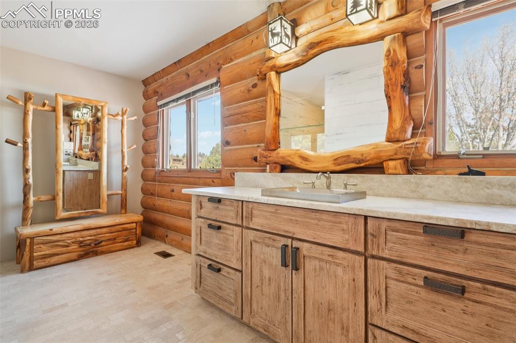 Bathroom with rustic walls, vanity, and tile floors