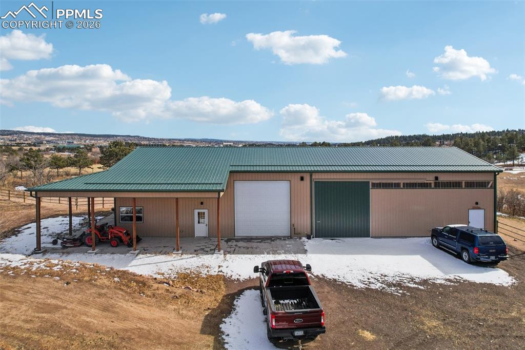 View of front of house featuring a metal roof, a detached garage, and an outdoor structure
