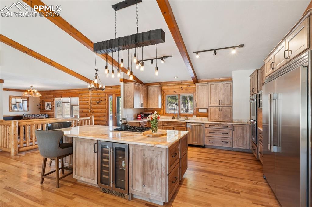 Kitchen featuring stainless steel appliances, open floor plan,beverage cooler, and a kitchen breakfast bar