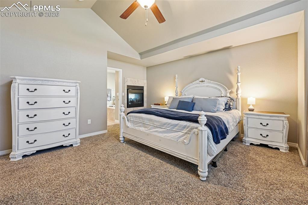 Bedroom featuring vaulted ceiling, carpet flooring, a ceiling fan, and ensuite bathroom
