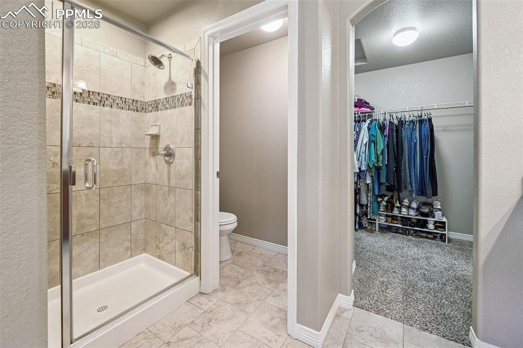 Full bath with light carpet, a spacious closet, and a stall shower