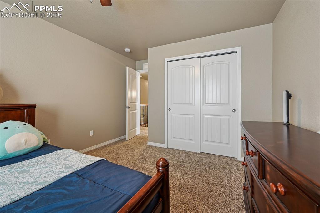 Bedroom with light carpet, a closet, and a ceiling fan