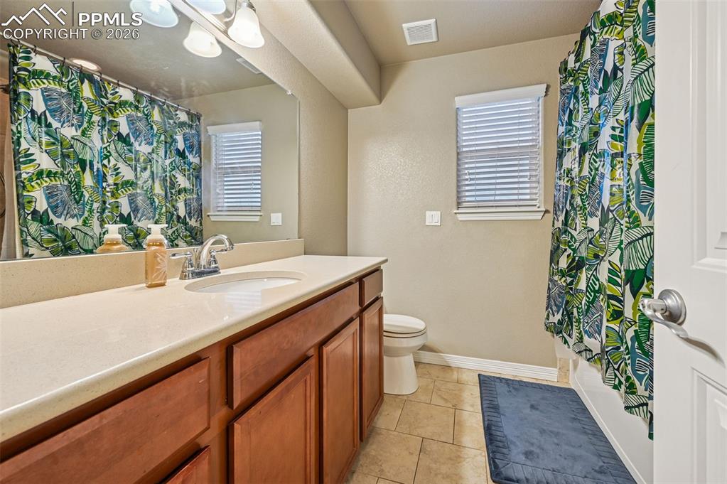 Full bath featuring vanity, light tile patterned floors, and shower / bath combo