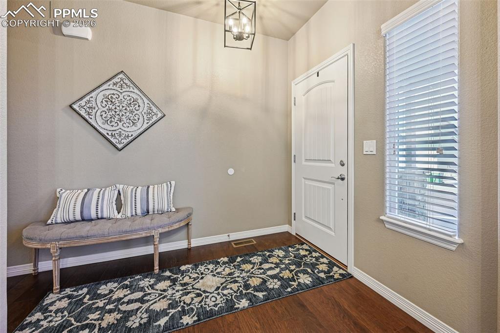 Foyer featuring hanging lights and dark wood-type flooring