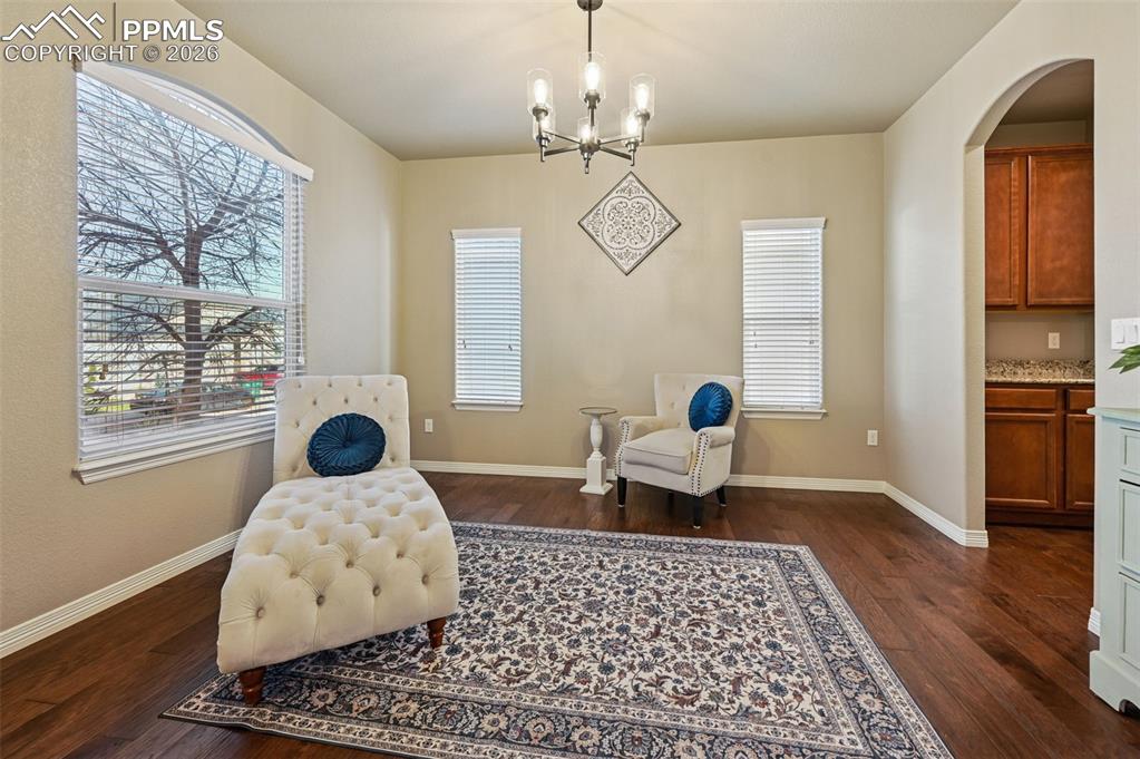 Sitting room featuring arched walkways, hanging lights, and dark wood finished floors