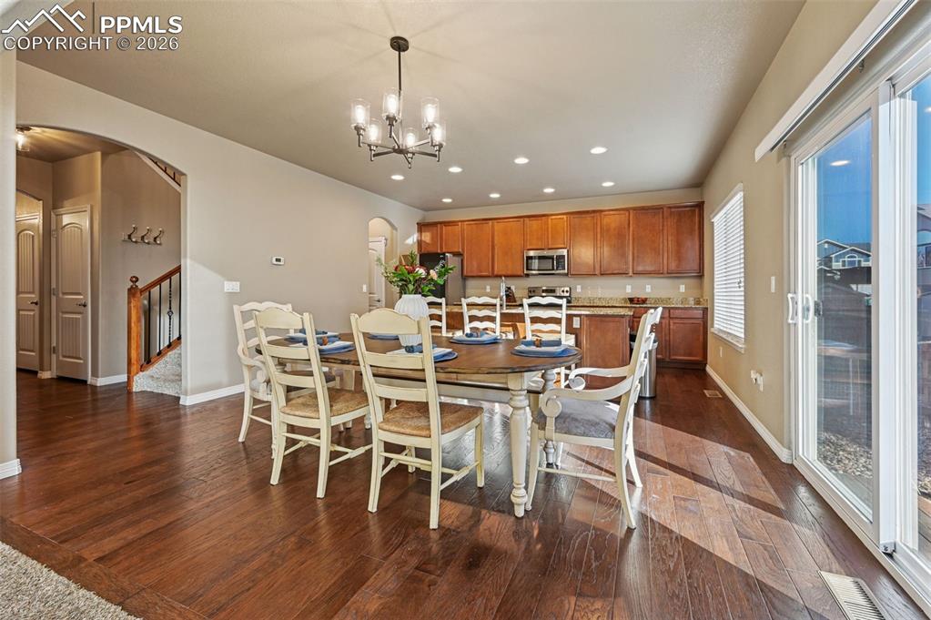 Dining space featuring arched walkways, dark wood-style floors, and a chandelier