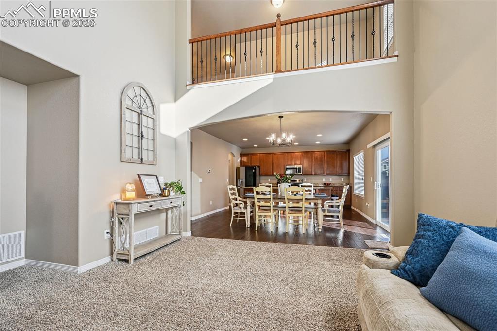 Dining room with a high ceiling, hanging lights, and dark carpet
