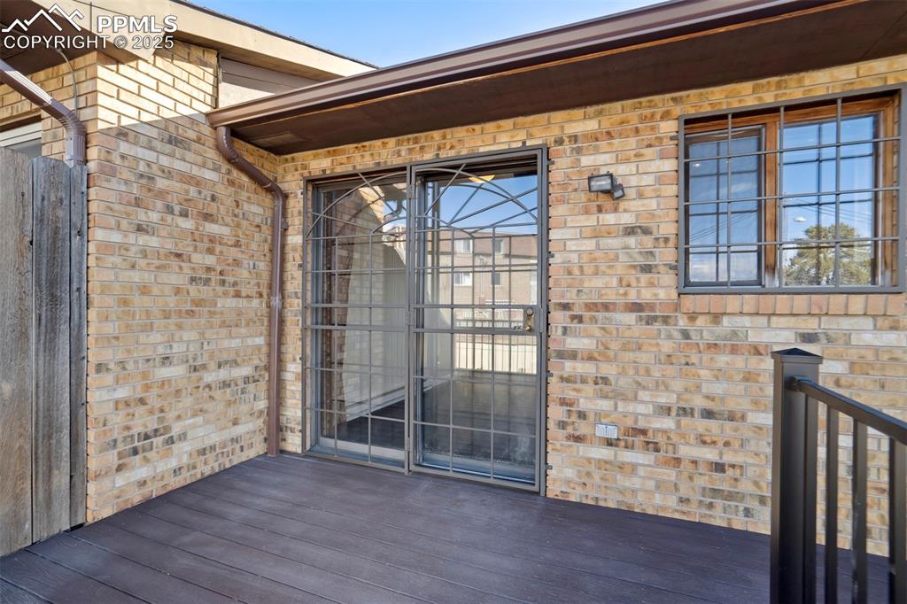 Property entrance with brick siding and a wooden deck