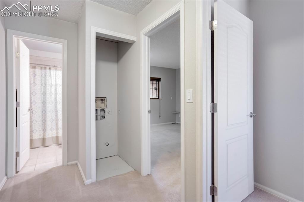 Hall with light colored carpet and a textured ceiling.  New w/d just installed!