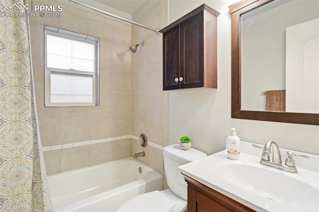 Bathroom with vanity, shower / bath combo with shower curtain, and a textured wall