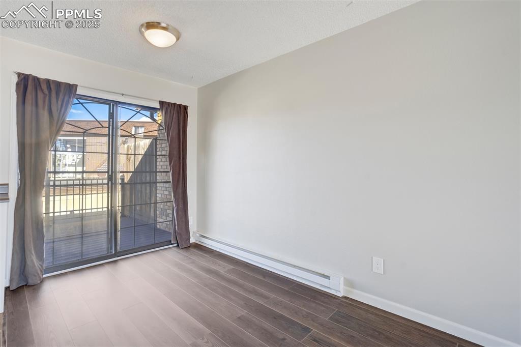 Unfurnished room with baseboard heating, dark wood-type flooring, and a textured ceiling