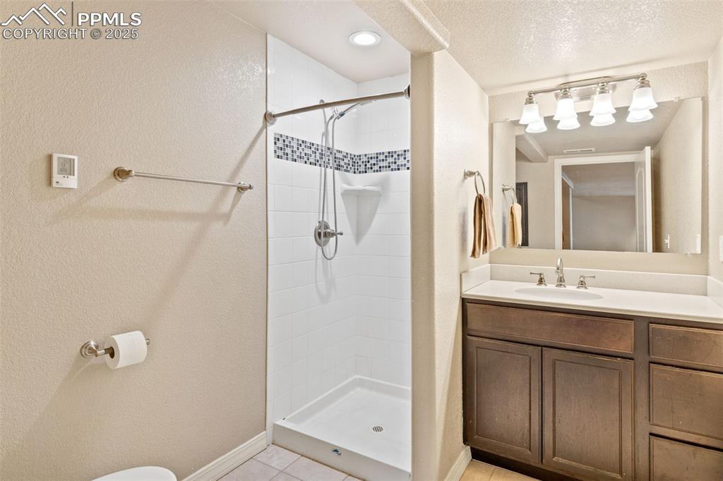 Basement 3/4 bath features a tiled walk-in shower and tiled flooring.