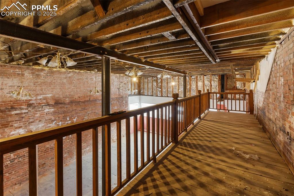 Expansive storefront interior with exposed brick, tall ceilings, and loft/mezzanine potential