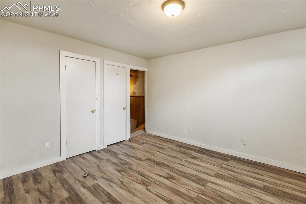 Unfurnished bedroom featuring wood finished floors and baseboards