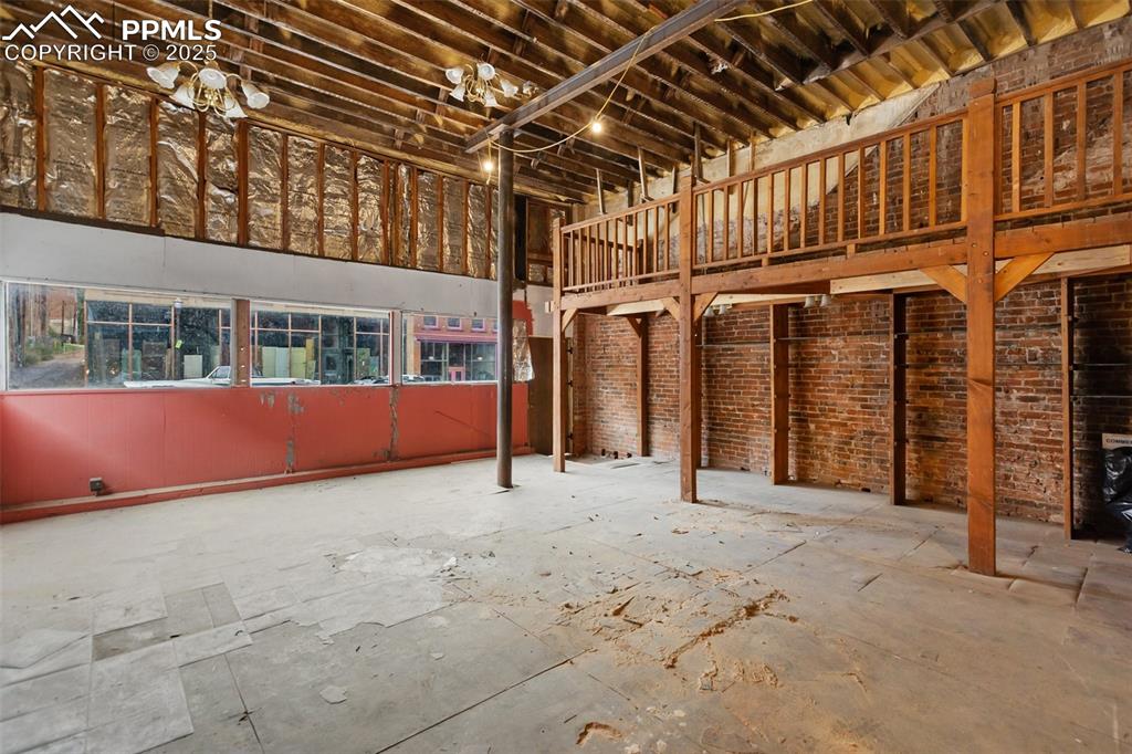 Large open storefront interior with exposed brick walls and high ceilings — ready for build-out