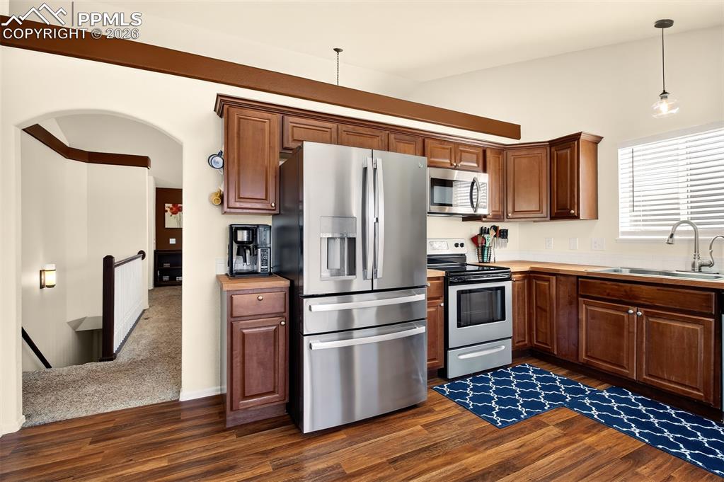 Kitchen with stainless sleet appliances, plenty of cabinet space, butcher block countertops and a walk out