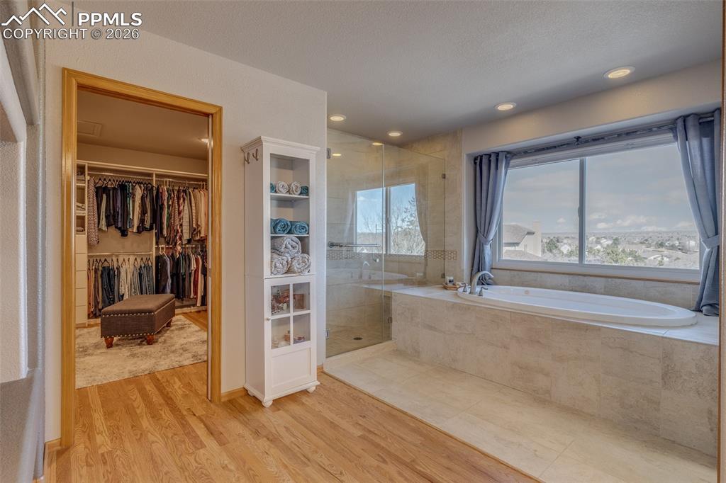 Full bathroom with a garden tub, a walk in closet, a shower stall, light wood-style flooring, and recessed lighting