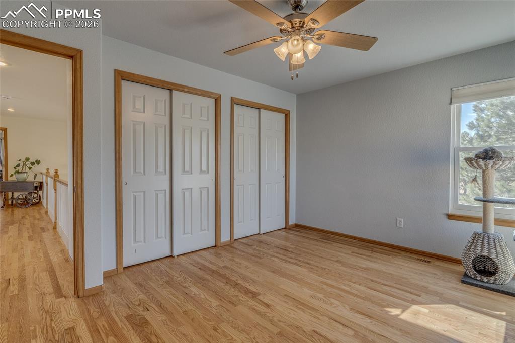 Unfurnished bedroom with two closets, light wood-style flooring, and a ceiling fan
