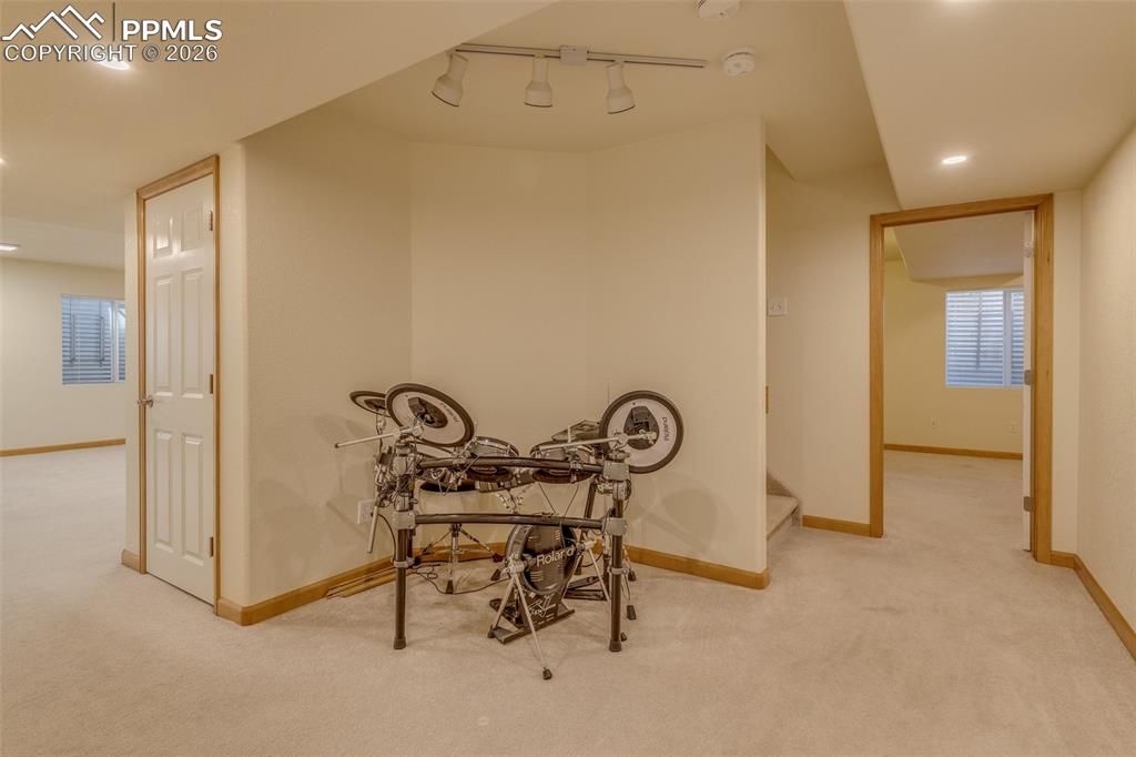 Hallway featuring light carpet and rail lighting