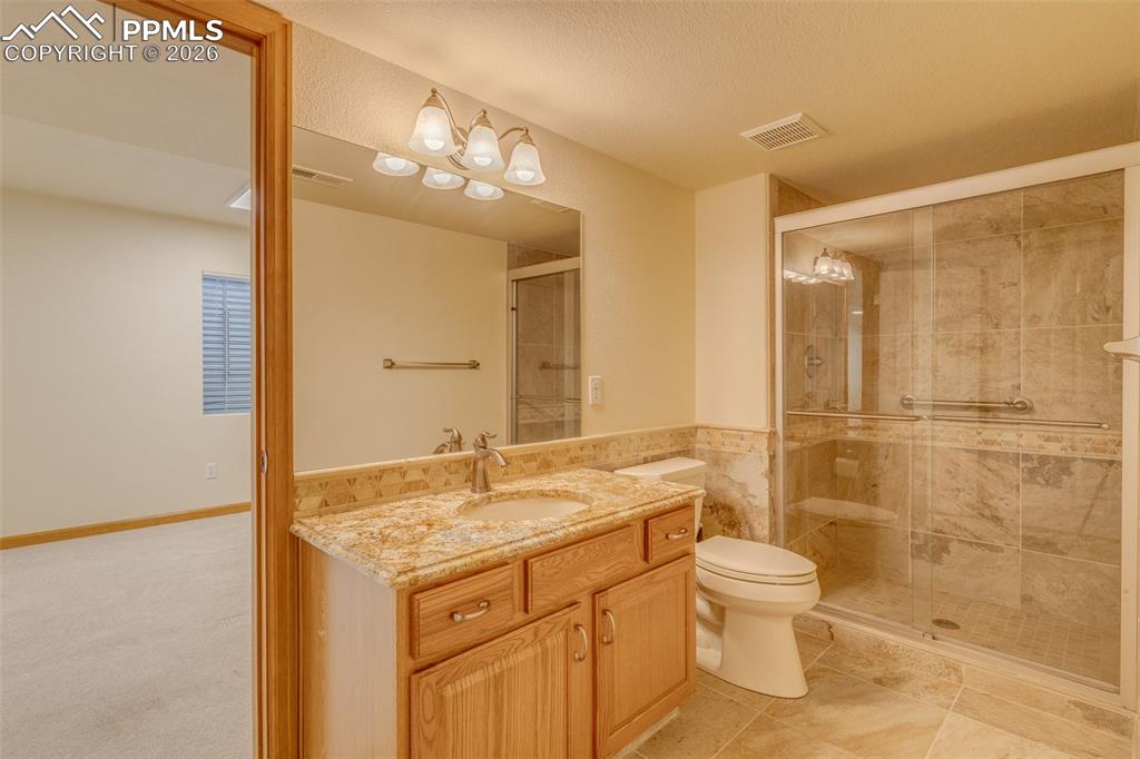 Bathroom with vanity, a shower stall, tile walls, and a textured ceiling