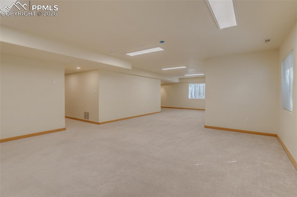 Basement with light colored carpet and baseboards