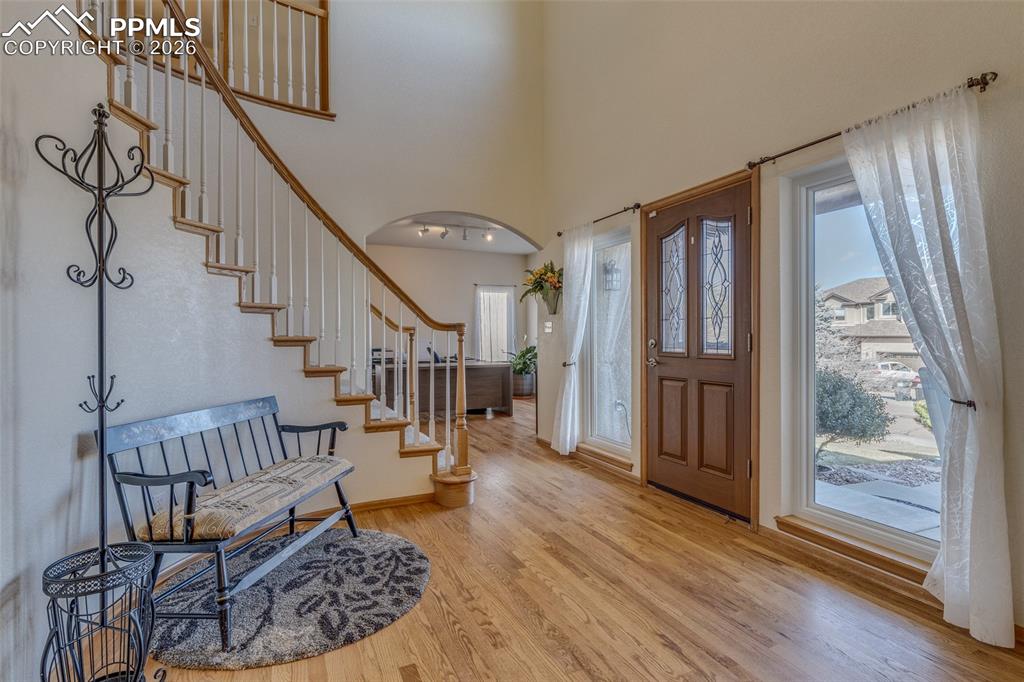 Entrance foyer with a high ceiling, arched walkways, and light wood-style flooring