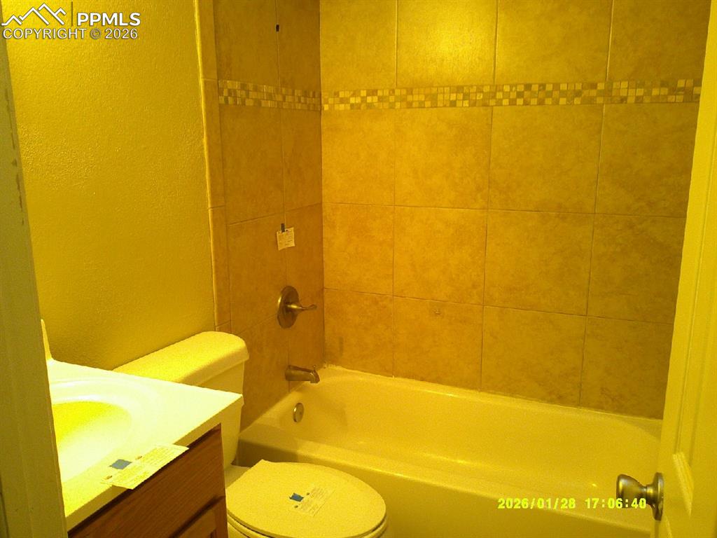 Full bath with a textured wall, vanity, and washtub / shower combination