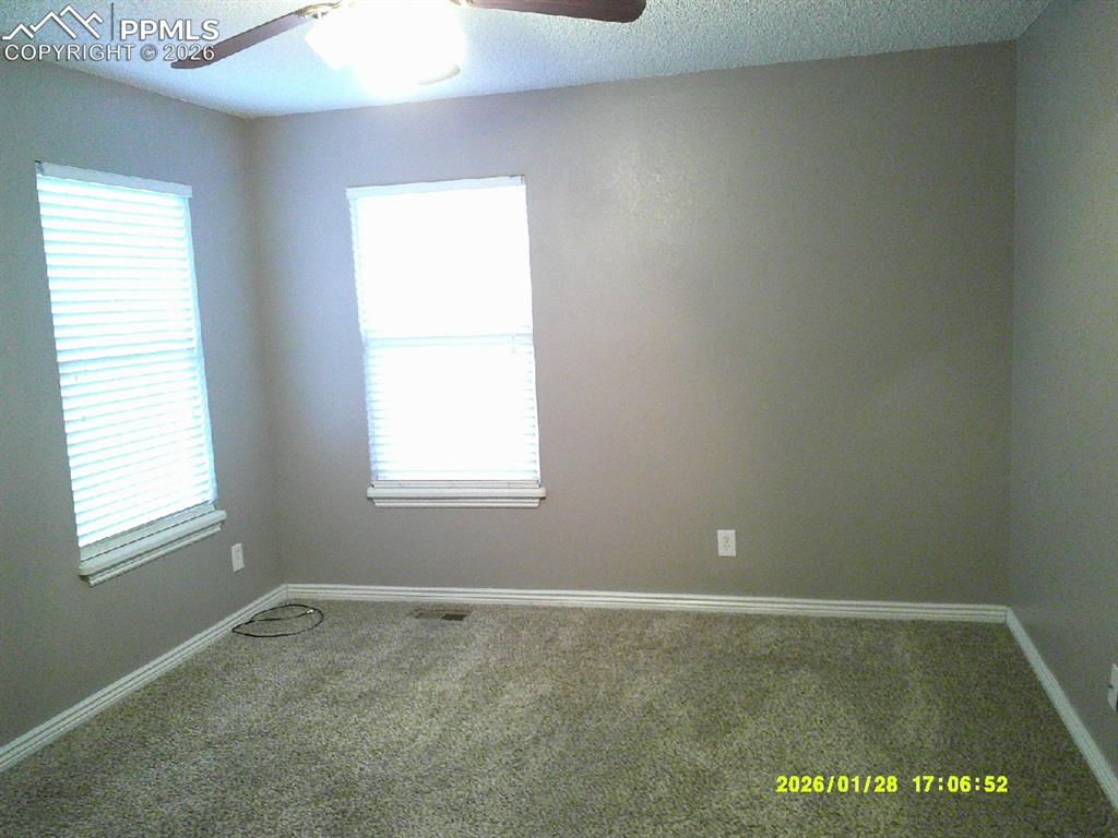 Carpeted empty room featuring a ceiling fan and a textured ceiling