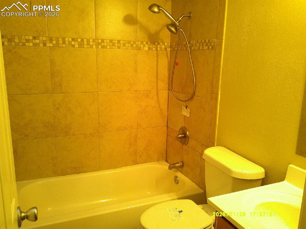 Full bath with a textured wall, vanity, and washtub / shower combination
