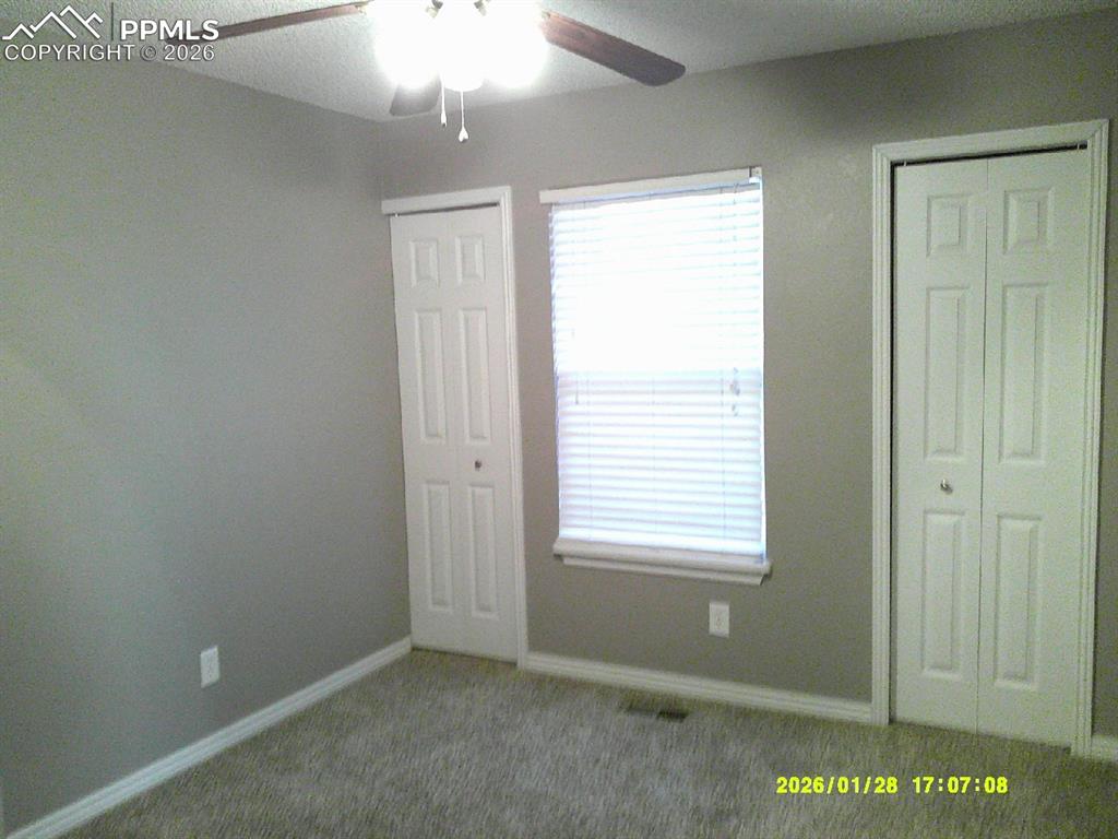 Unfurnished bedroom with multiple closets, carpet flooring, and a ceiling fan