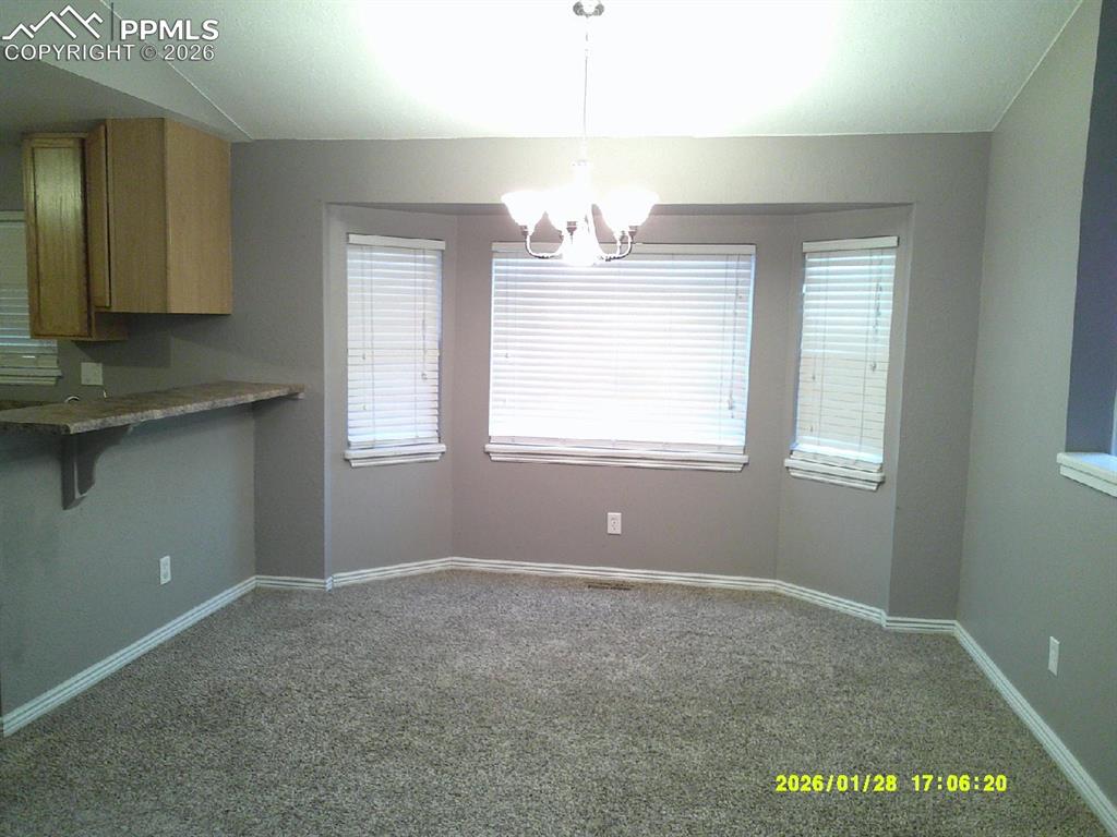 Unfurnished dining area with dark carpet and hanging lights