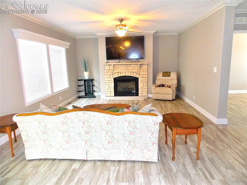 Living room featuring a brick fireplace, light hardwood / wood-style flooring, and ceiling fan