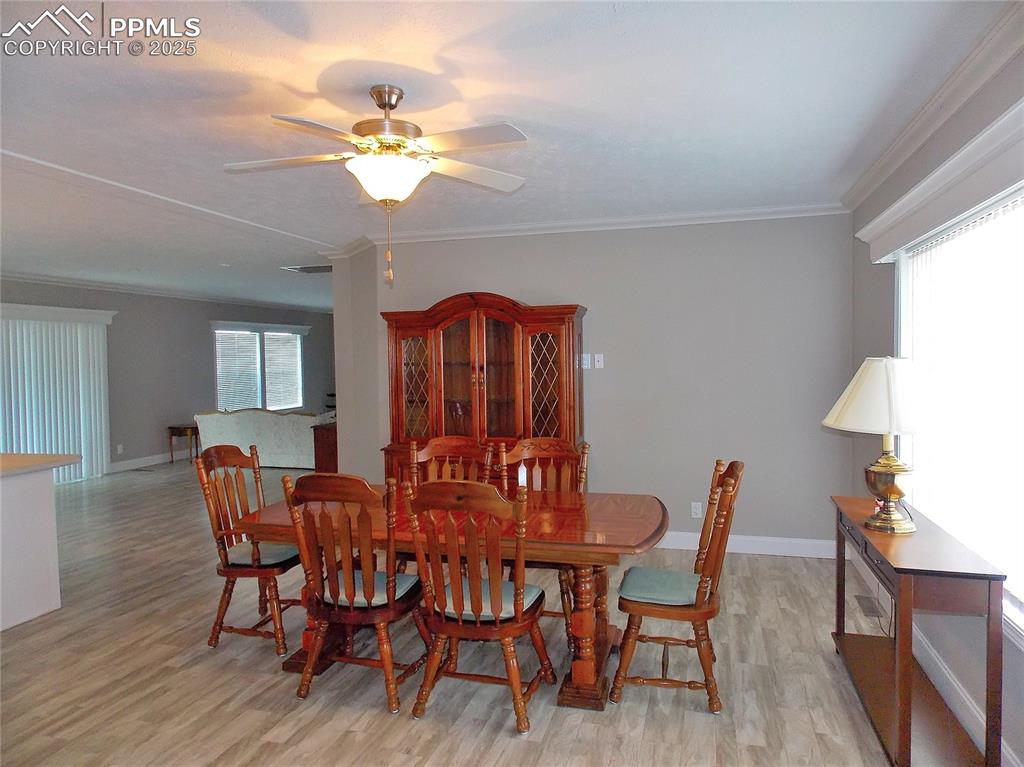 Dining room featuring ceiling fan, light, crown molding, and picture window