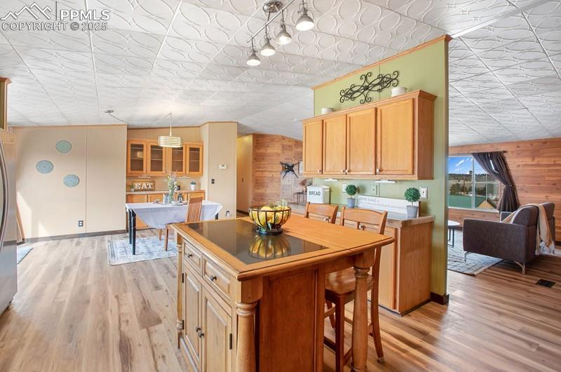 Kitchen with an ornate ceiling, light wood-style flooring, a kitchen island, and wooden walls