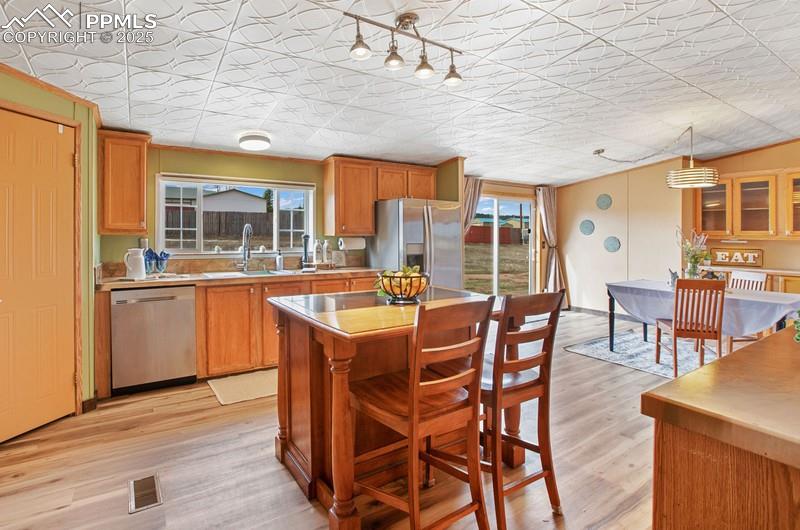 Kitchen featuring light wood-type flooring, a kitchen island, a wealth of natural light, and stainless steel appliances