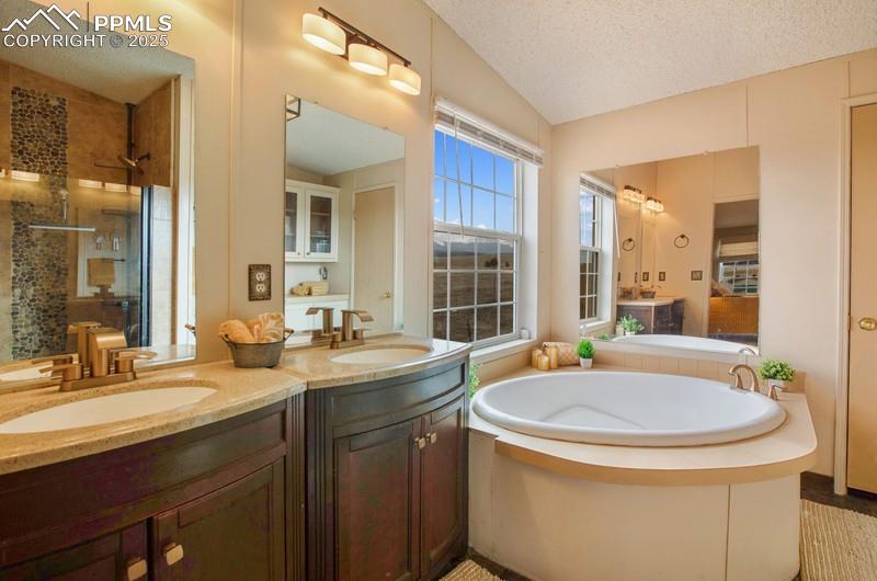 Bathroom featuring tiled shower, a garden tub, and a sink