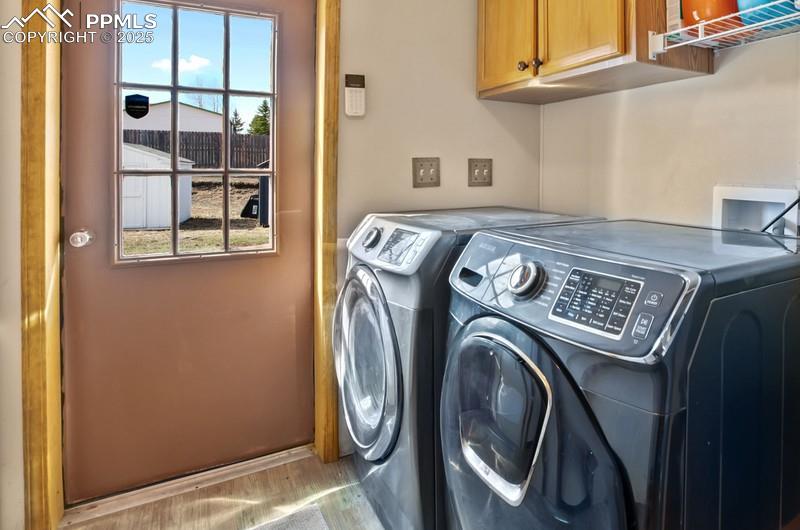 Laundry room featuring wood finished floors, washing machine and clothes dryer, and cabinet space