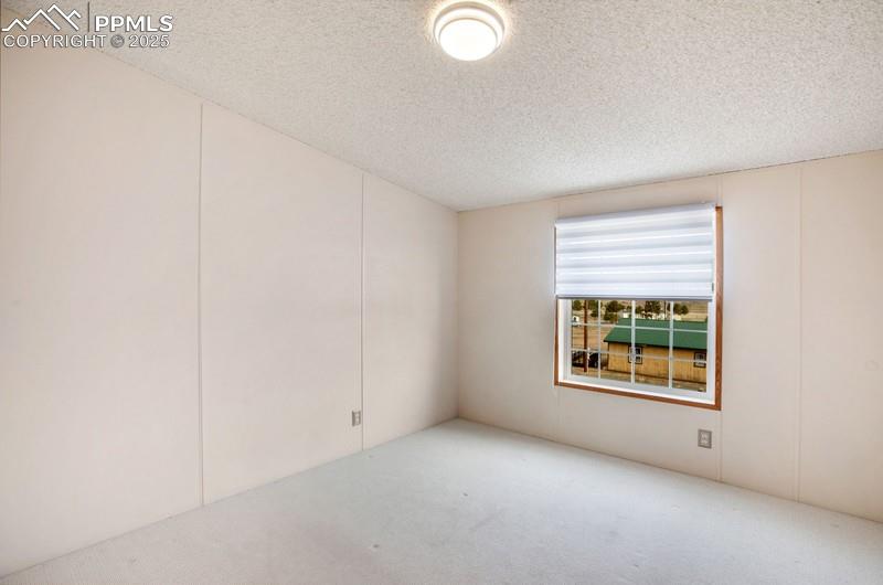 Carpeted empty room featuring a textured ceiling