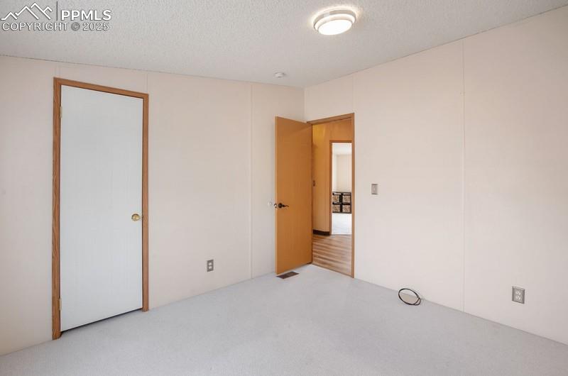 Unfurnished bedroom featuring visible vents, carpet, and a textured ceiling