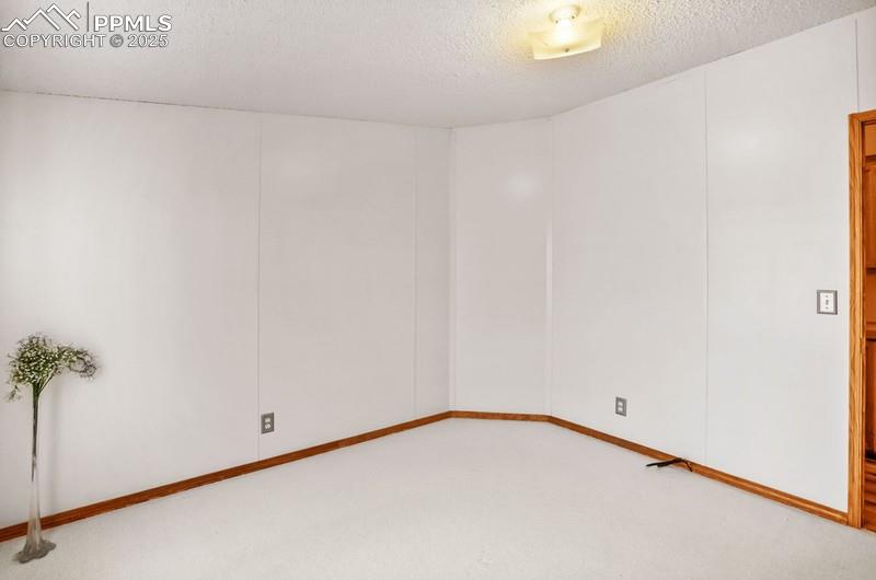 Empty room featuring light carpet and a textured ceiling