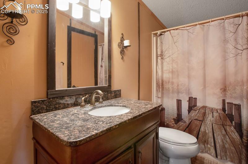 Full bathroom with toilet, a textured ceiling, and vanity
