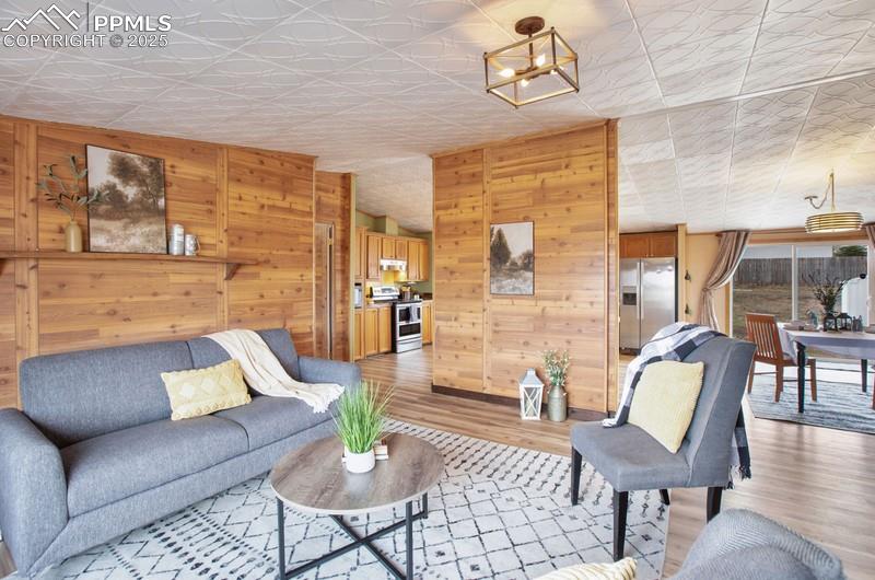Living room with wooden walls, an ornate ceiling, and light wood finished floors
