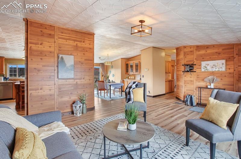 Living room with wooden walls, light wood-type flooring, baseboards, and lofted ceiling