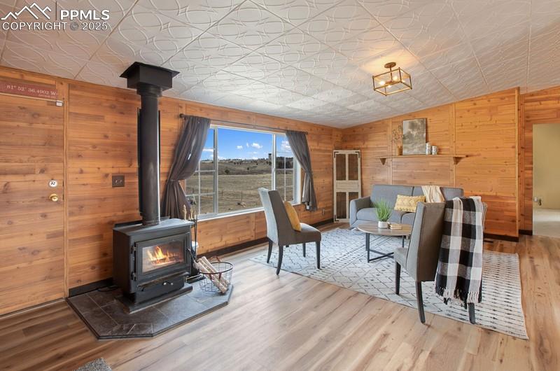 Living room with wood finished floors, wooden walls, an ornate ceiling, and a wood stove